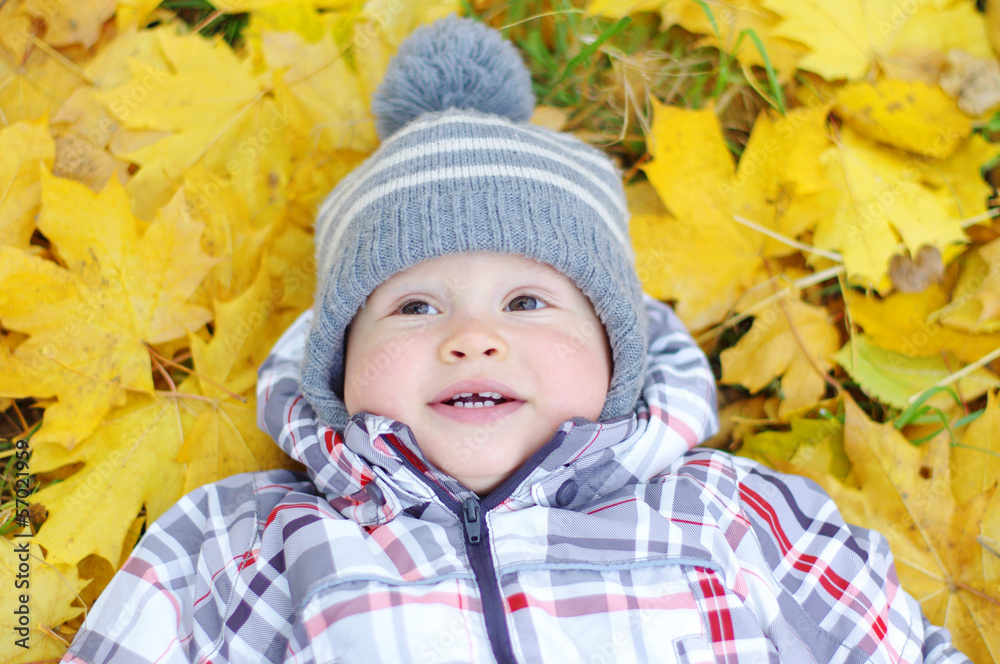 portrait of lovely baby lying against yellow leaves portrait of lovely baby lying against yellow leaves