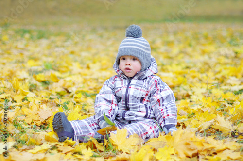 lovely baby age of 1 year outdoors in autumn against leaves