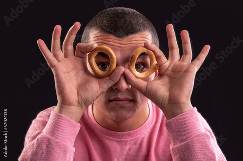 Billede på lærred cheerful teenager look through a bagels hole