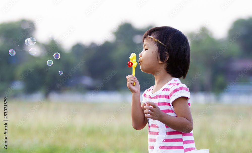 Asian little girl is blowing a soap bubbles