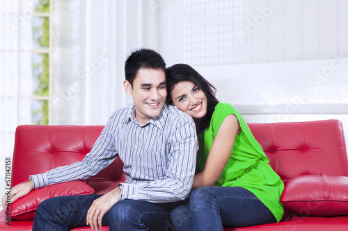 Young couple relaxing on a red sofa at home