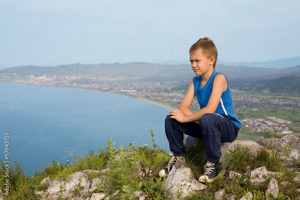 Boy traveler on top of a mountain.