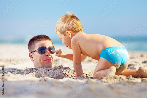 Billede på lærred father and son having fun in sand on the beach