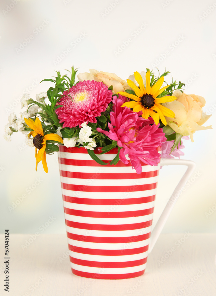 Beautiful bouquet of bright flowers in color mug,