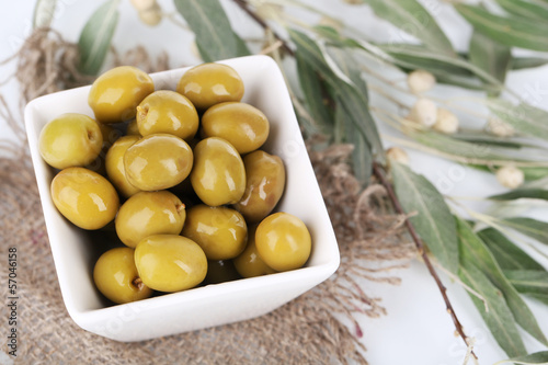 Olives in bowl with branch on sackcloth close up