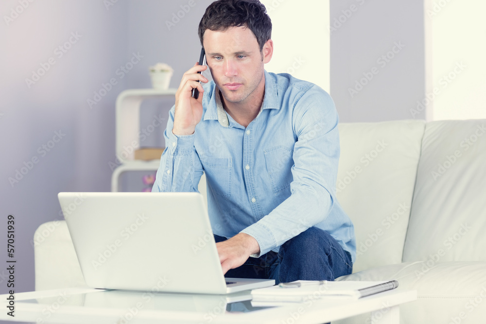 Handsome casual man using laptop and phoning Handsome casual man using laptop and phoning