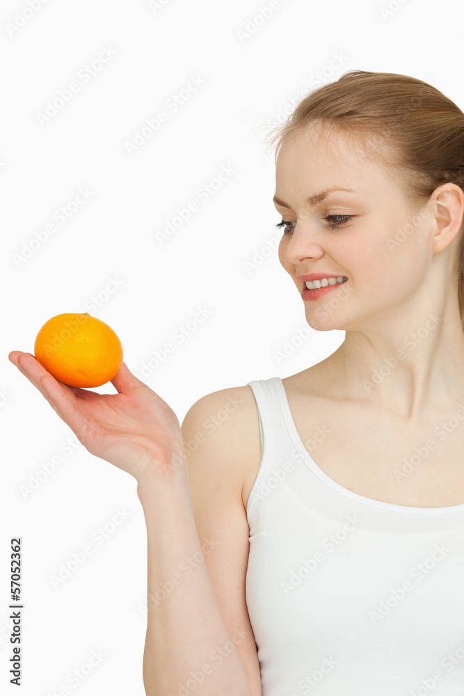 Smiling woman presenting a tangerine while looking at it Smiling woman presenting a tangerine while looking at it