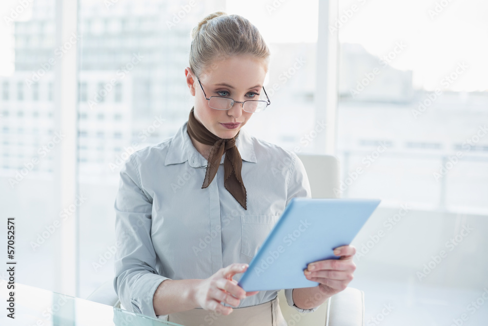 Blonde stern businesswoman looking at tablet Blonde stern businesswoman looking at tablet