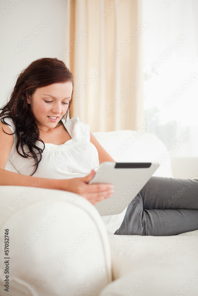 Beautiful red-haired woman relaxing on a sofa with a tablet Beautiful red-haired woman relaxing on a sofa with a tablet
