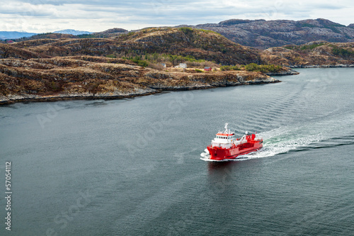 Small Norwegian red oil products tanker ship sails in fjord