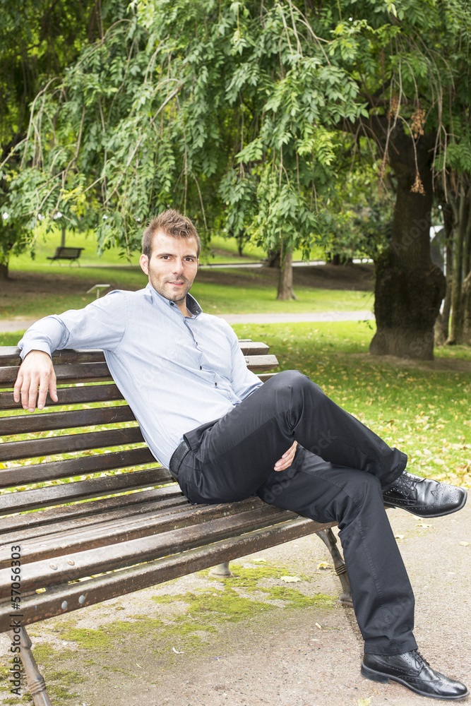 Obraz premium Man sitting and relaxing on a bench in the park.