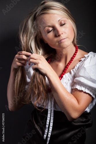 Folk woman in folklore clothes braiding a plait