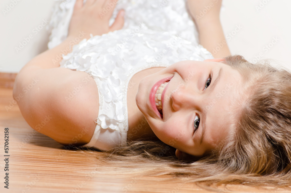 Naklejka premium Happy kid lying on floor smiling and looking into camera