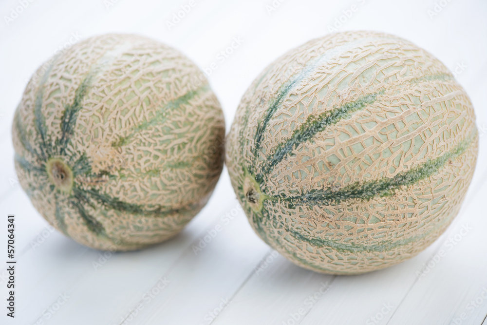 Two ripe cantaloupe melons on white wooden boards, studio shot Two ripe cantaloupe melons on white wooden boards, studio shot