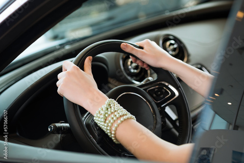 woman s hands holding on to the wheel of a new car