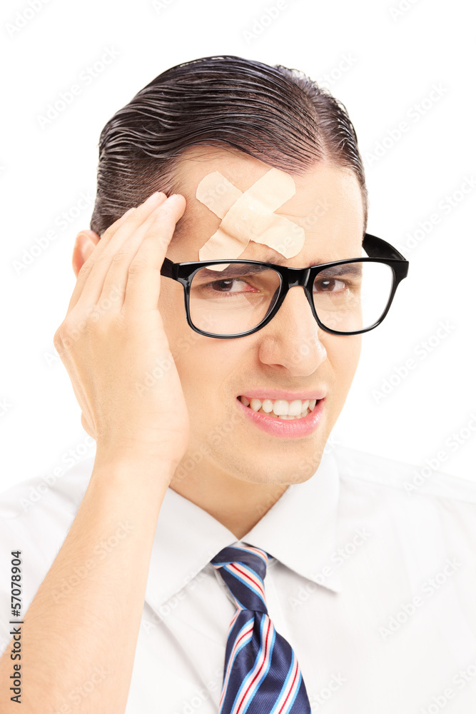 Serious young man with plaster on his forehead having a headache