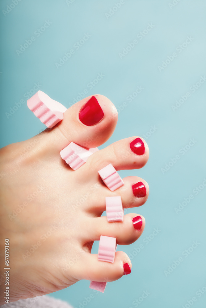 foot pedicure applying red toenails on blue foot pedicure applying red toenails on blue