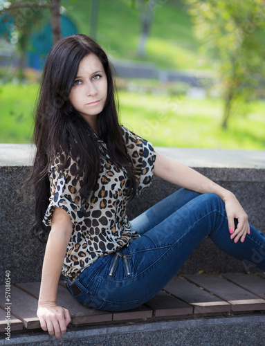 Beautiful young woman sits on a bench.