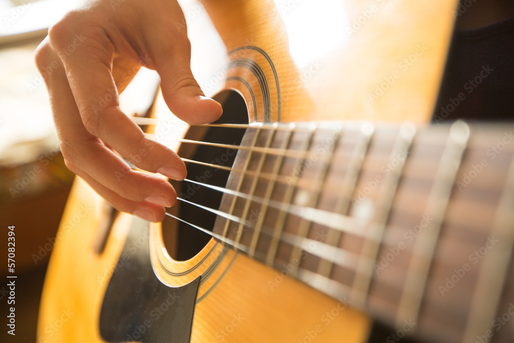 Fototapeta premium Female hand playing on acoustic guitar. Close-up.