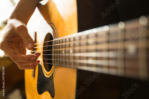 Close-up female hand playing on acoustic guitar..
