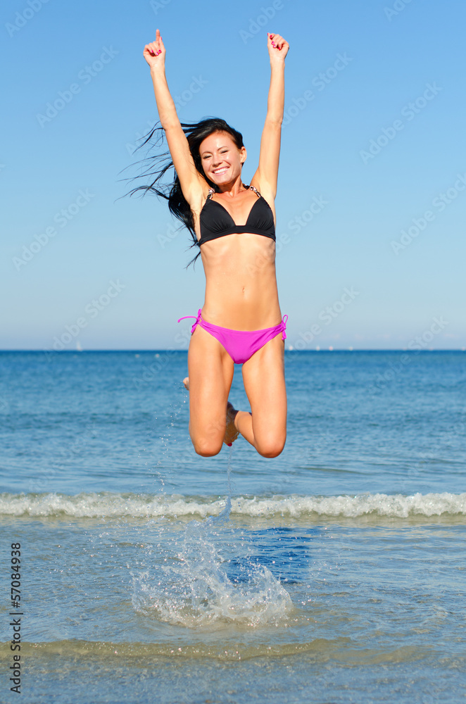 Happy woman jumping in the water at the beach Happy woman jumping in the water at the beach