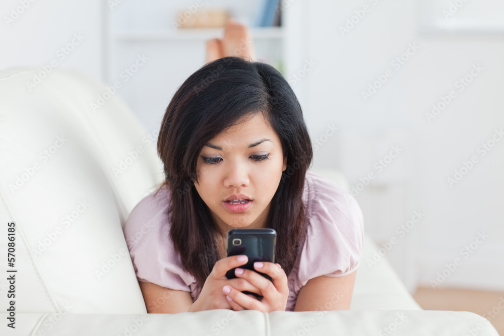 Surprised woman looking at a phone on a sofa Surprised woman looking at a phone on a sofa