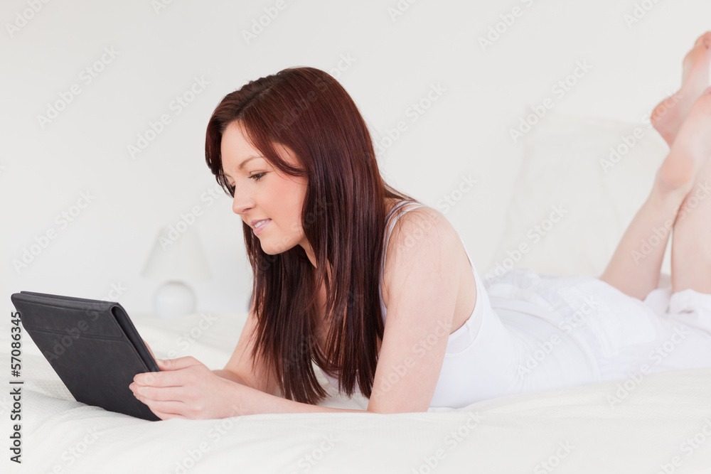 Attractive red-haired female relaxing with her tablet Attractive red-haired female relaxing with her tablet