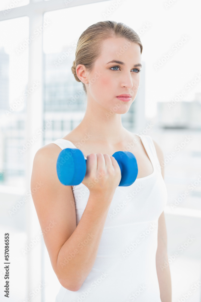 Pensive fit woman exercising with dumbbells Pensive fit woman exercising with dumbbells