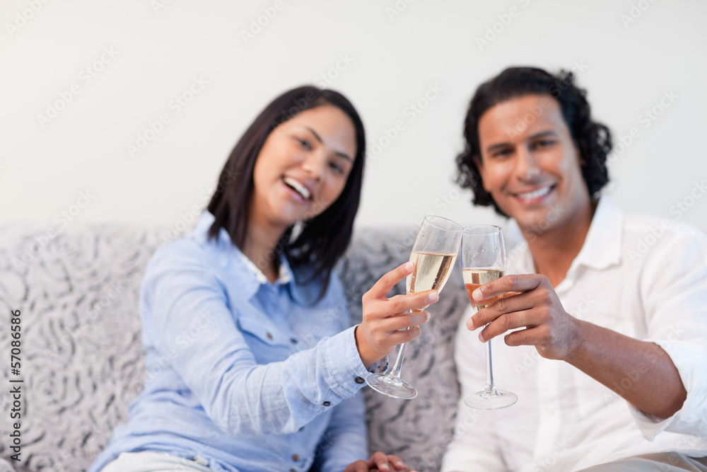Couple celebrating with sparkling wine on the couch Couple celebrating with sparkling wine on the couch