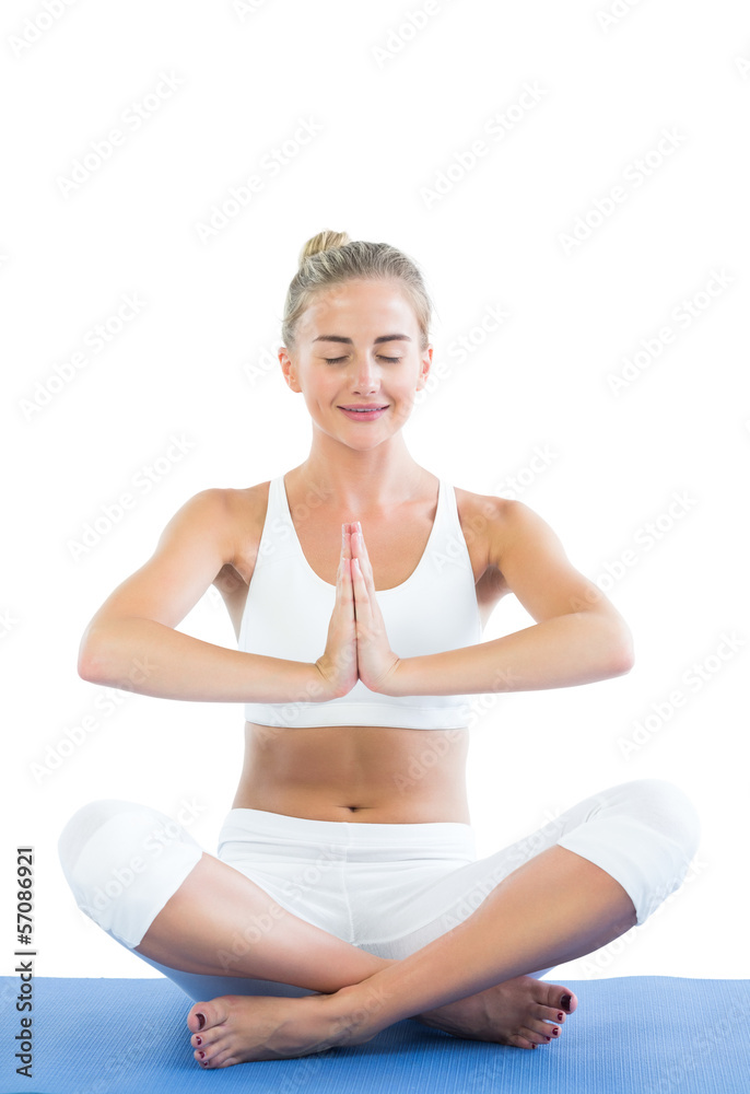 Toned smiling blonde sitting in lotus pose meditating