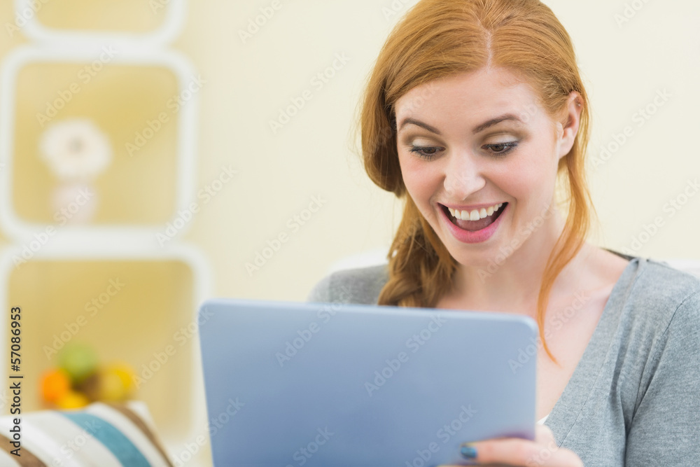 Surprised redhead sitting on the couch using tablet Surprised redhead sitting on the couch using tablet