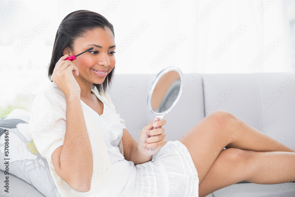 Stylish young dark haired woman in white clothes applying mascar Stylish young dark haired woman in white clothes applying mascar