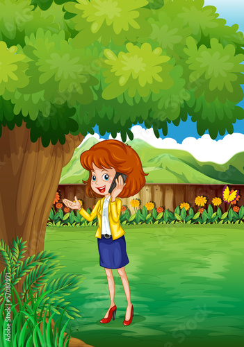 A woman with a cellphone standing under the tree