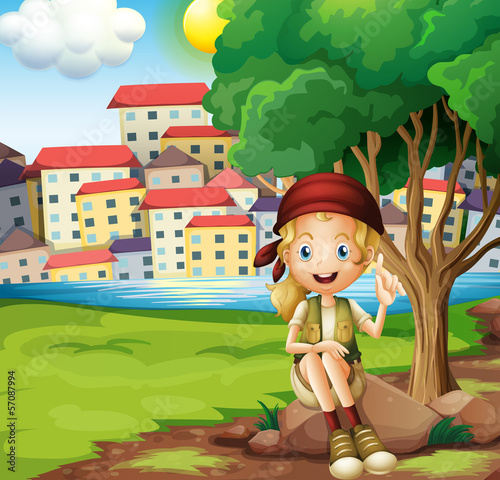 A girl sitting above the rock under the tree