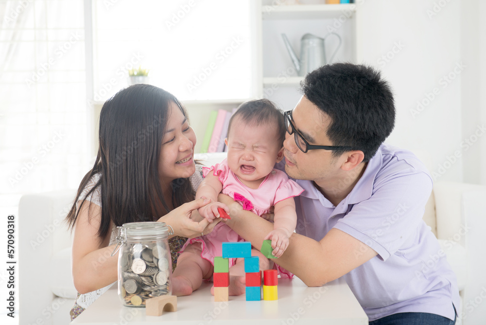 crying asian baby being comforted by chinese parents