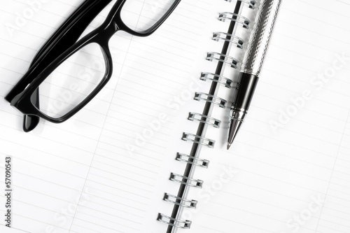 glass, notebook and business pen on table