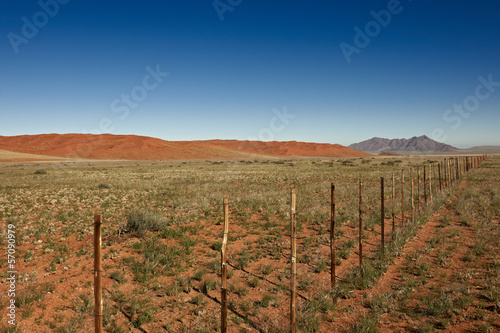 endloser Zaun durch Wuestenlandschaft der Namib, Namibia,Africa