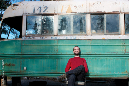 Young man sitting in front of Magic Bus from Into The Wild