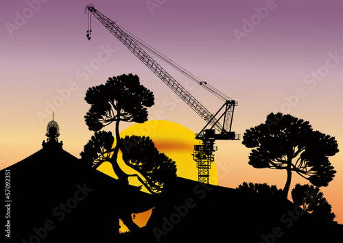 tower crane and trees at yellow sunset