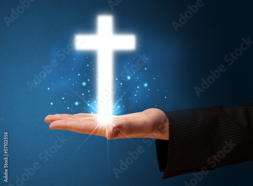 Glowing cross in the hand of a businessman