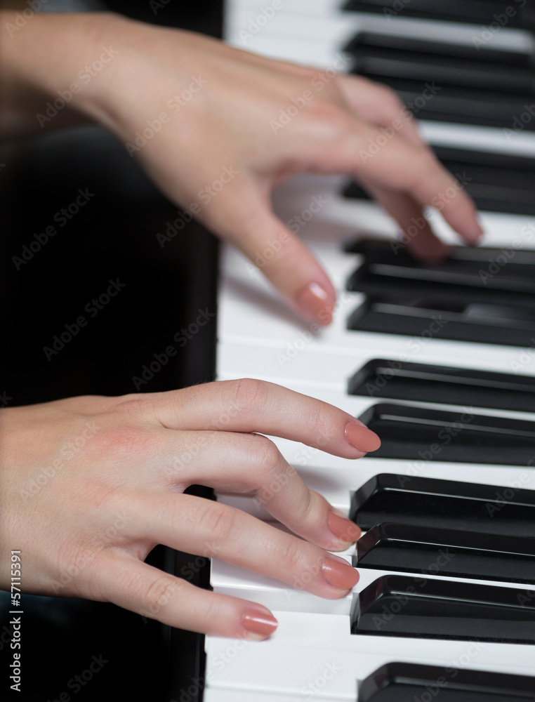 Fototapeta premium A hand of a girl playing piano. Selective focus.
