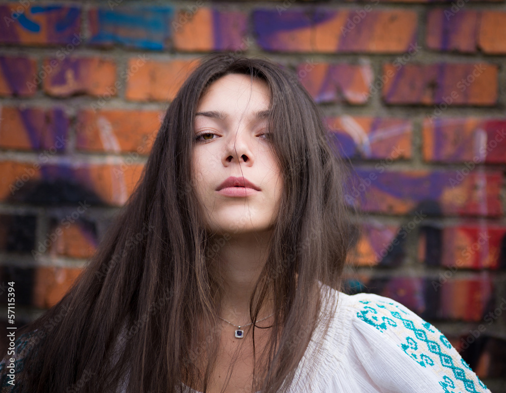 Naklejka premium Portrait of a girl posing over brick wall.