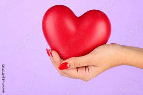 Red heart in woman s hand on color background