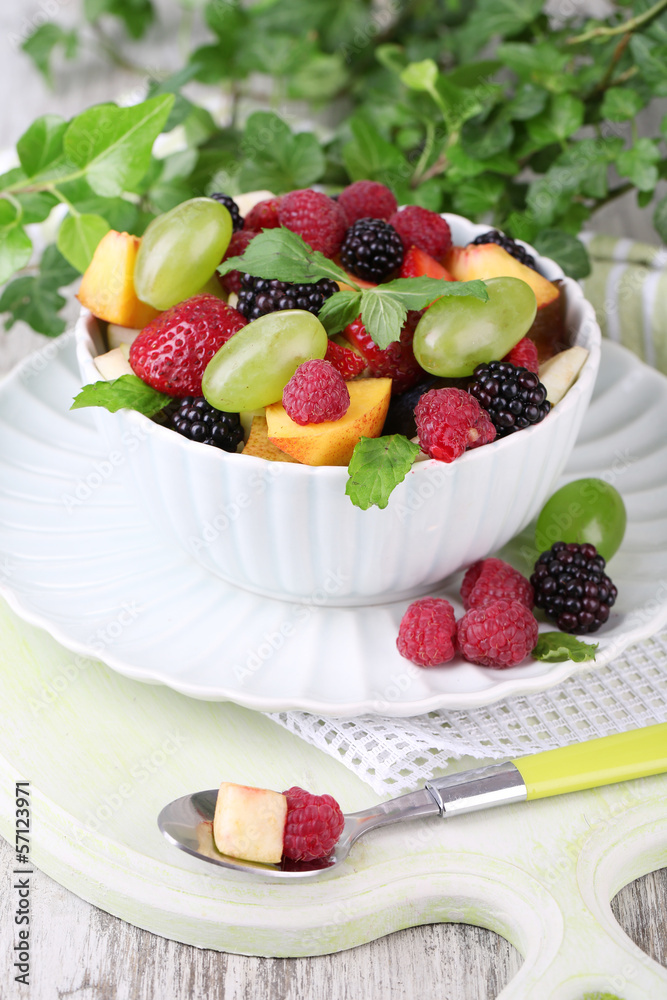 Fruit salad in bowl, on wooden table, on bright background Fruit salad in bowl, on wooden table, on bright background
