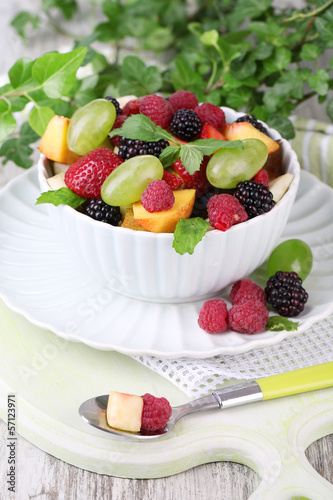 Fruit salad in bowl  on wooden table  on bright background