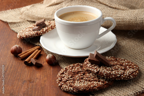 Cup of tasty coffee with tasty cookies, on wooden background