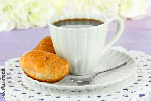 Tasty croissants and cup of coffee on table close-up