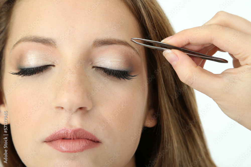 Young woman having eye-brows plucked isolated on white Young woman having eye-brows plucked isolated on white