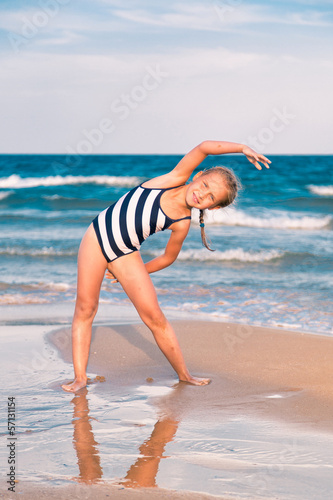 Beautiful little girl excercising on the beach © len44ik