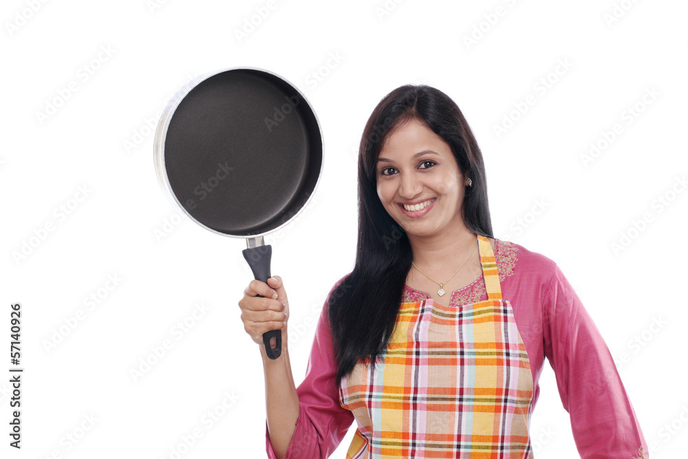 Young Indian woman holding kitchen utensil against white Young Indian woman holding kitchen utensil against white